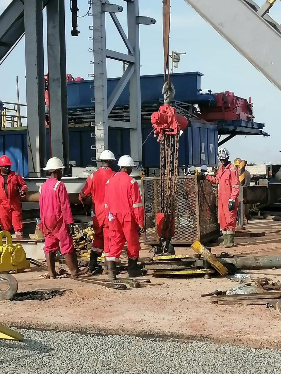 Rig floor crew working around suspended heavy equipment
