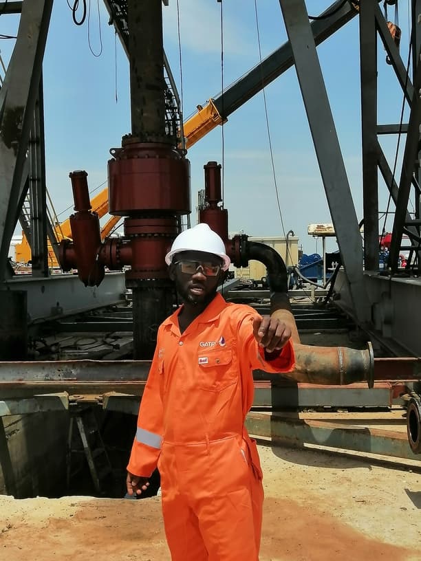 GGSL supervisor in orange coveralls in front of rig equipment